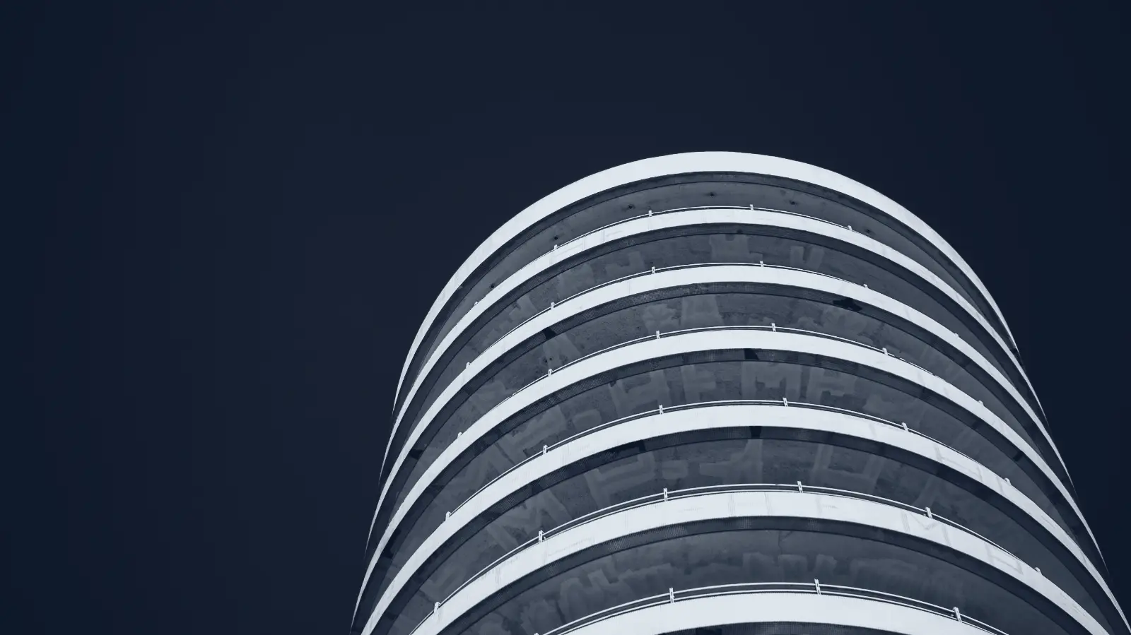 The curved facade of a modern office building, seen from below.