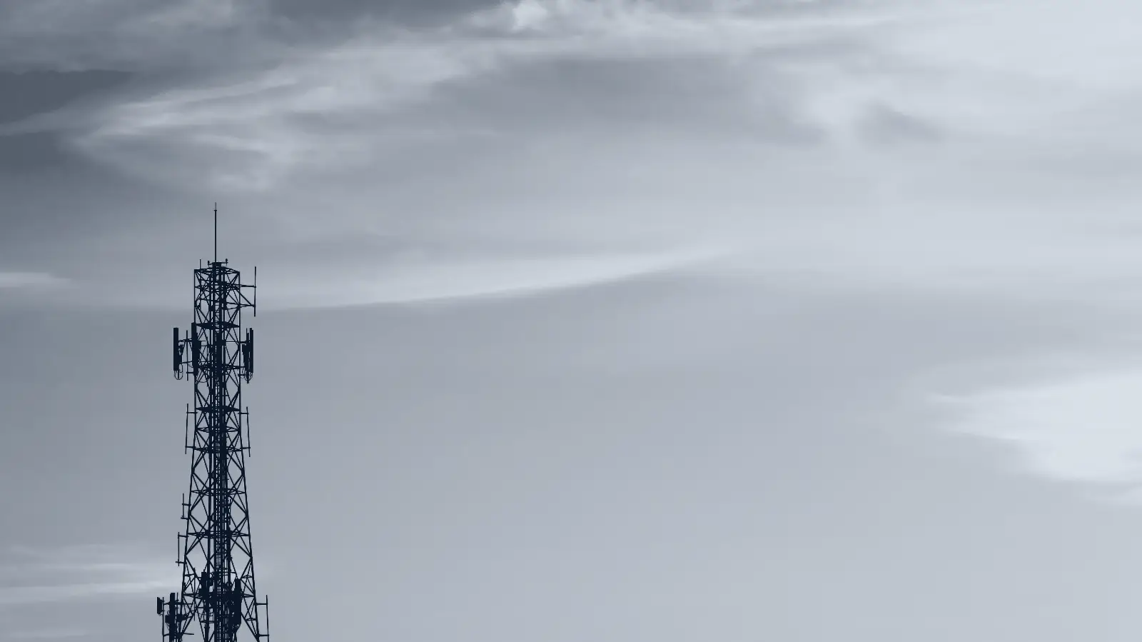 A telecommunications tower against an open sky at dusk.