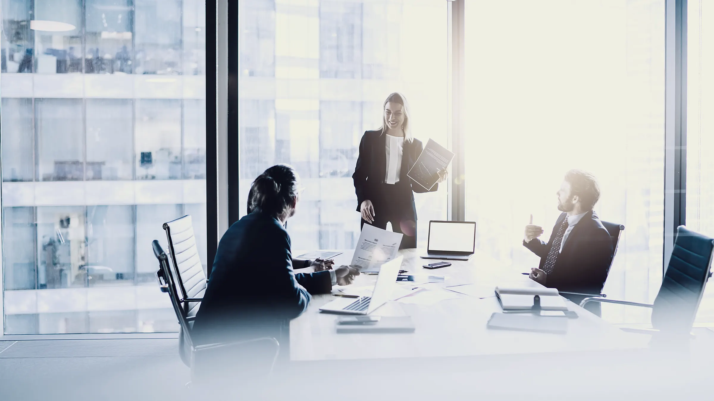 An executive meeting in a glass-walled office high above the city.