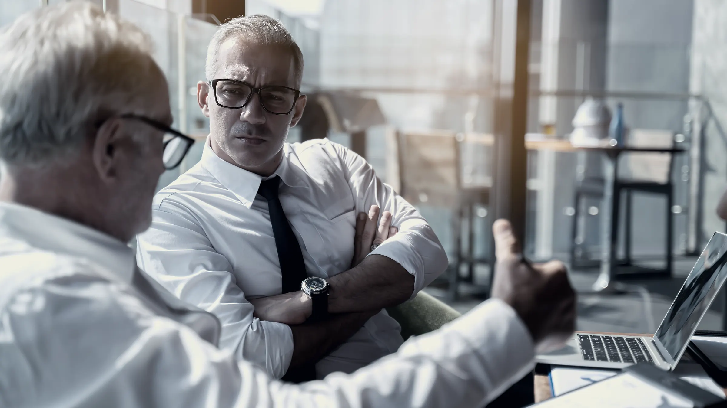 Two senior investors in conversation before a meeting.